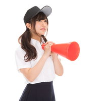 赤いメガホン片手に応援する制服の女子高生の写真