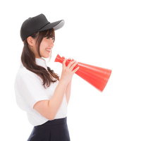 メガホンを持って笑顔で応援する野球部の女子マネの写真