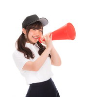 赤いメガホンを持って笑顔で応援する女子マネージャーの写真