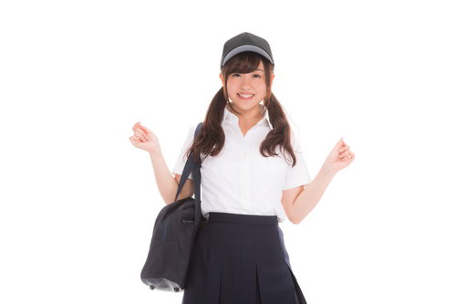 野球帽をかぶって野球部を応援する笑顔の女子高生