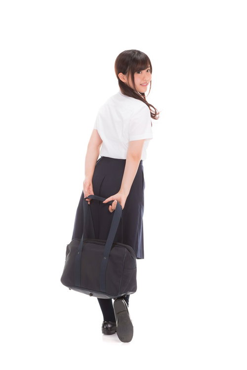 下校中に振り返る女子高生の後ろ姿、制服姿で歩く学生