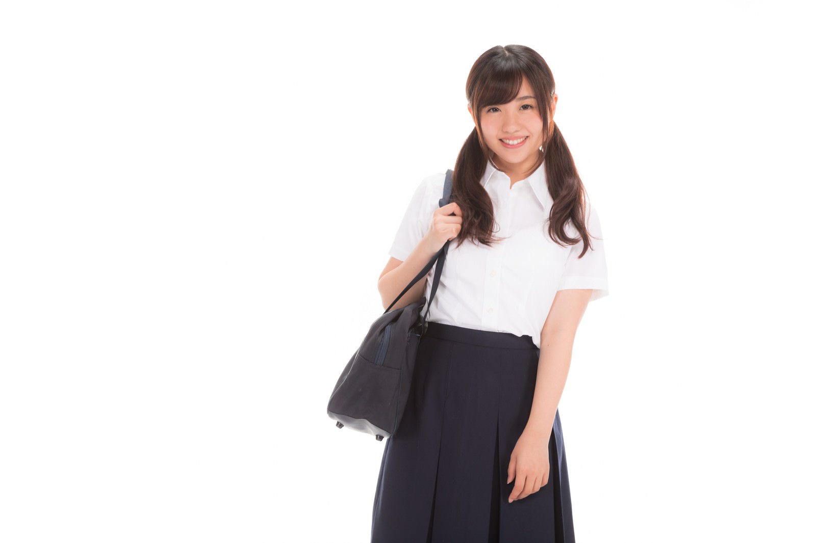 白いシャツと紺色のスカートを着て笑顔を見せる女子高生［モデル：河村友歌］