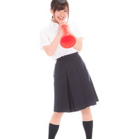 赤いメガホンで応援する女子高生の部活動応援シーンの写真