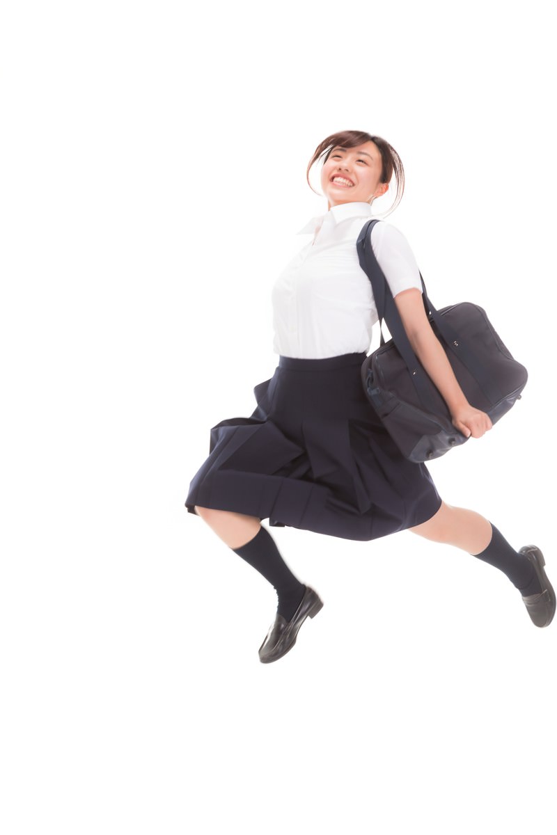 制服を着た女子高生が両手を上げて元気よくジャンプしている様子［モデル：河村友歌］