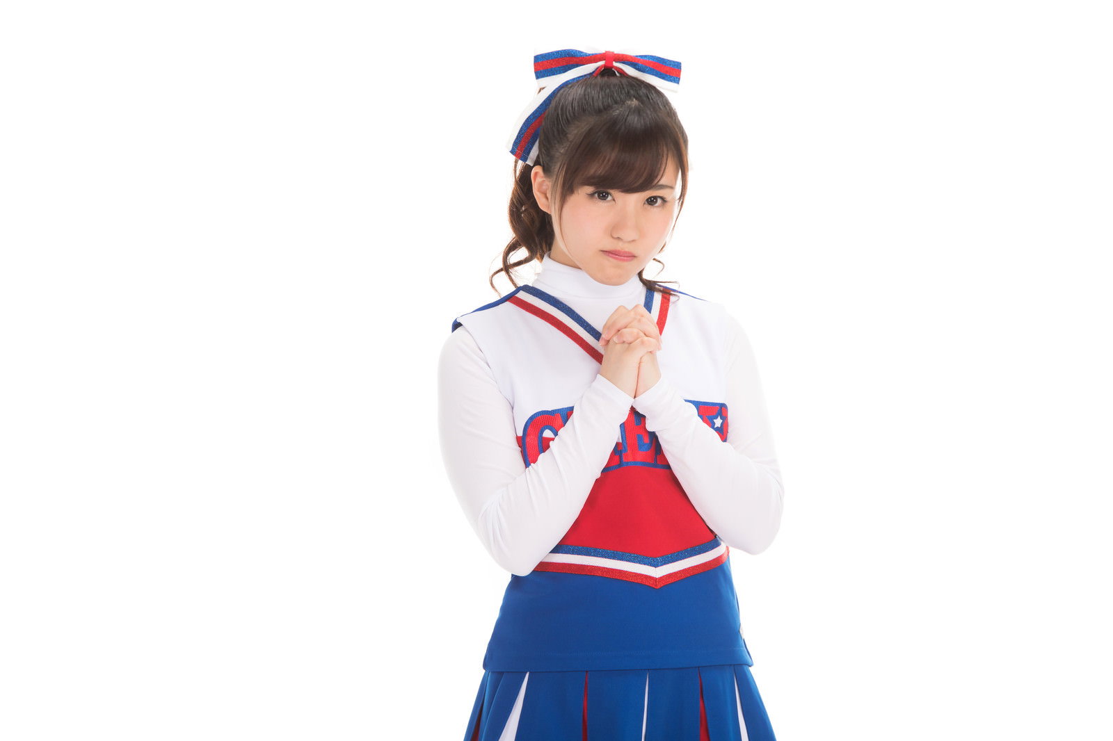 手を合わせてお願いポーズをする赤と青のチアユニフォーム姿の女性［モデル：河村友歌］