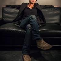 ソファーの上に大きく仰け反って偉そうにくつろぐ男性の写真