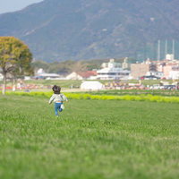 春の河川敷を走る子供 - 青空の下でのびのびと遊ぶ子どものの写真