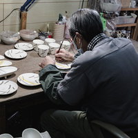 直方市の工房で陶器に絵付けする職人の背中の写真