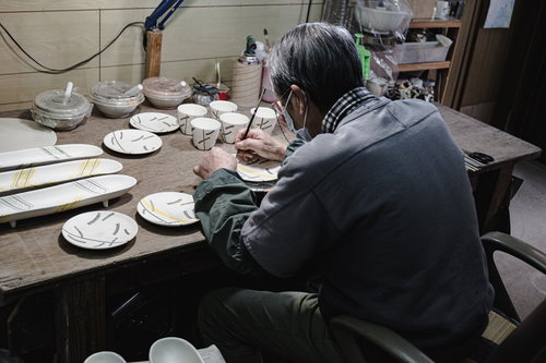 直方市の工房で陶器に絵付けする職人の背中