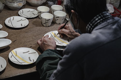 直方市の伝統工芸で陶器に絵付けする職人の後ろ姿