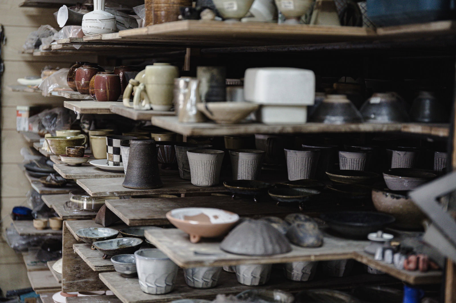 木製の棚に茶碗や皿などの陶器作品が整然と並べられている
