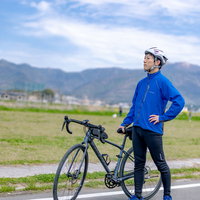 清々しい青空と福智山系を背にロードバイクを持つ直方市の男性の写真