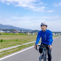 直線コースを走行する青いジャージのロードバイク男性の写真