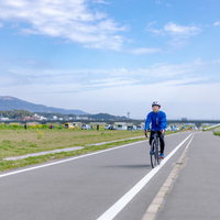 青空の下、直方北九州自転車道を走行するロードバイクの男性の写真