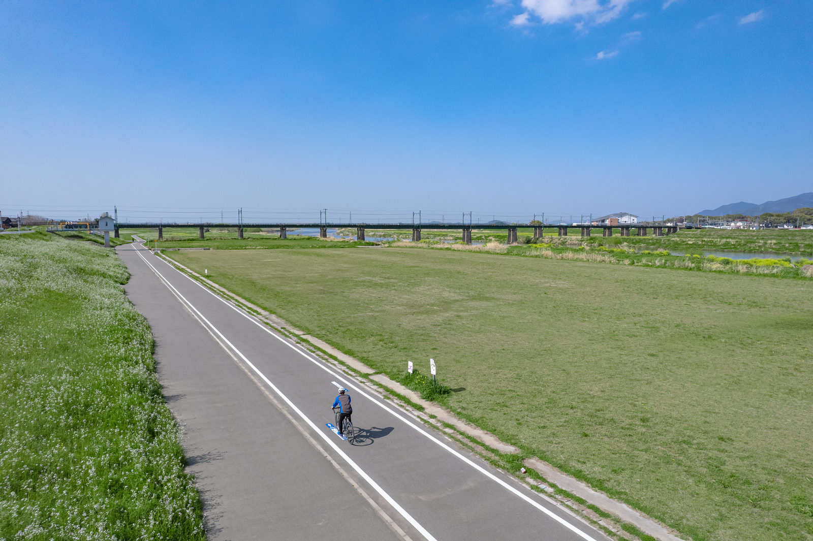 青空の下、筑豊鉄道沿いの専用道路をロードバイクで走る男性