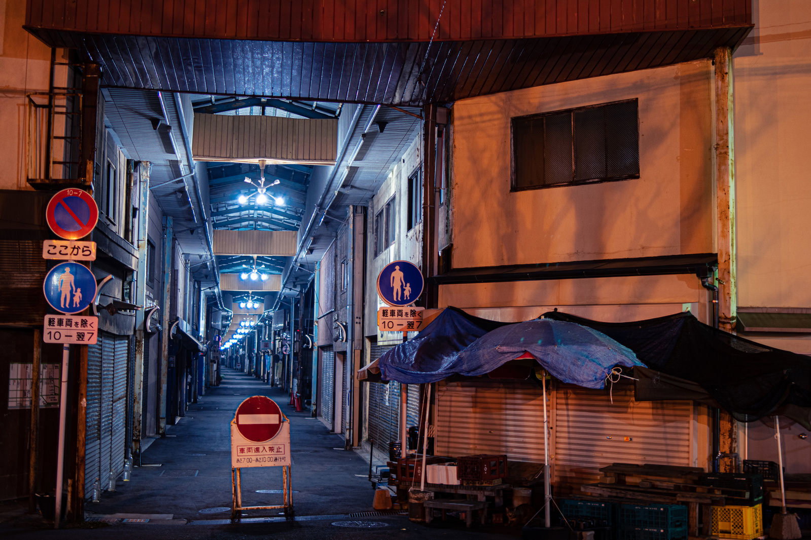 夜のアーケード商店街でシャッターが閉まった店舗が並ぶ風景