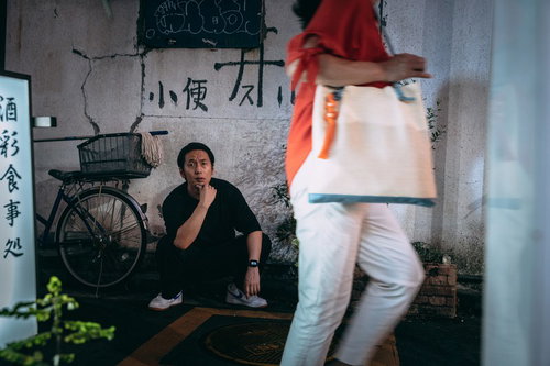 薄暗い路地で通りがかる女性を眺める男性の後ろ姿