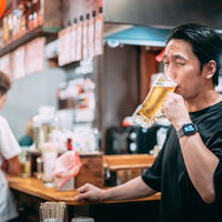居酒屋でビールをうまそうにごくごく飲む男性の写真