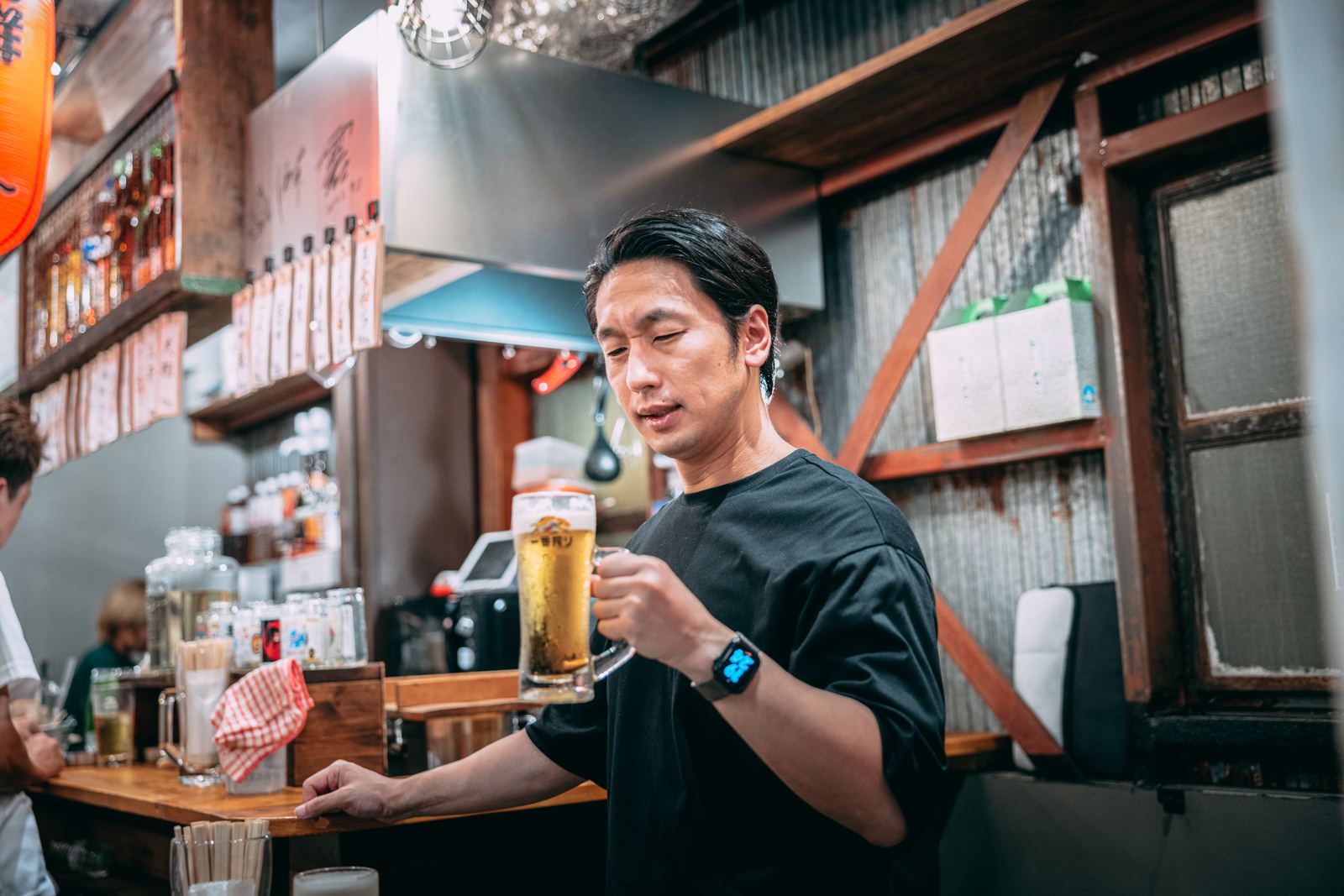 居酒屋で生ビールを飲む笑顔の男性［モデル：大川竜弥］