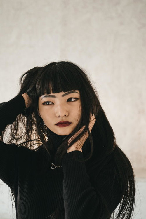 黒い前髪と赤い唇のオンザ眉毛メイク、ぱっつん前髪のポートレート