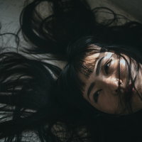 髪の毛がバッサーと絡まる床に横たわる女性のポートレートの写真