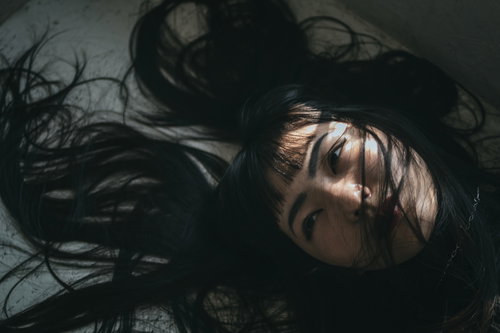 髪の毛がバッサーと絡まる床に横たわる女性のポートレート