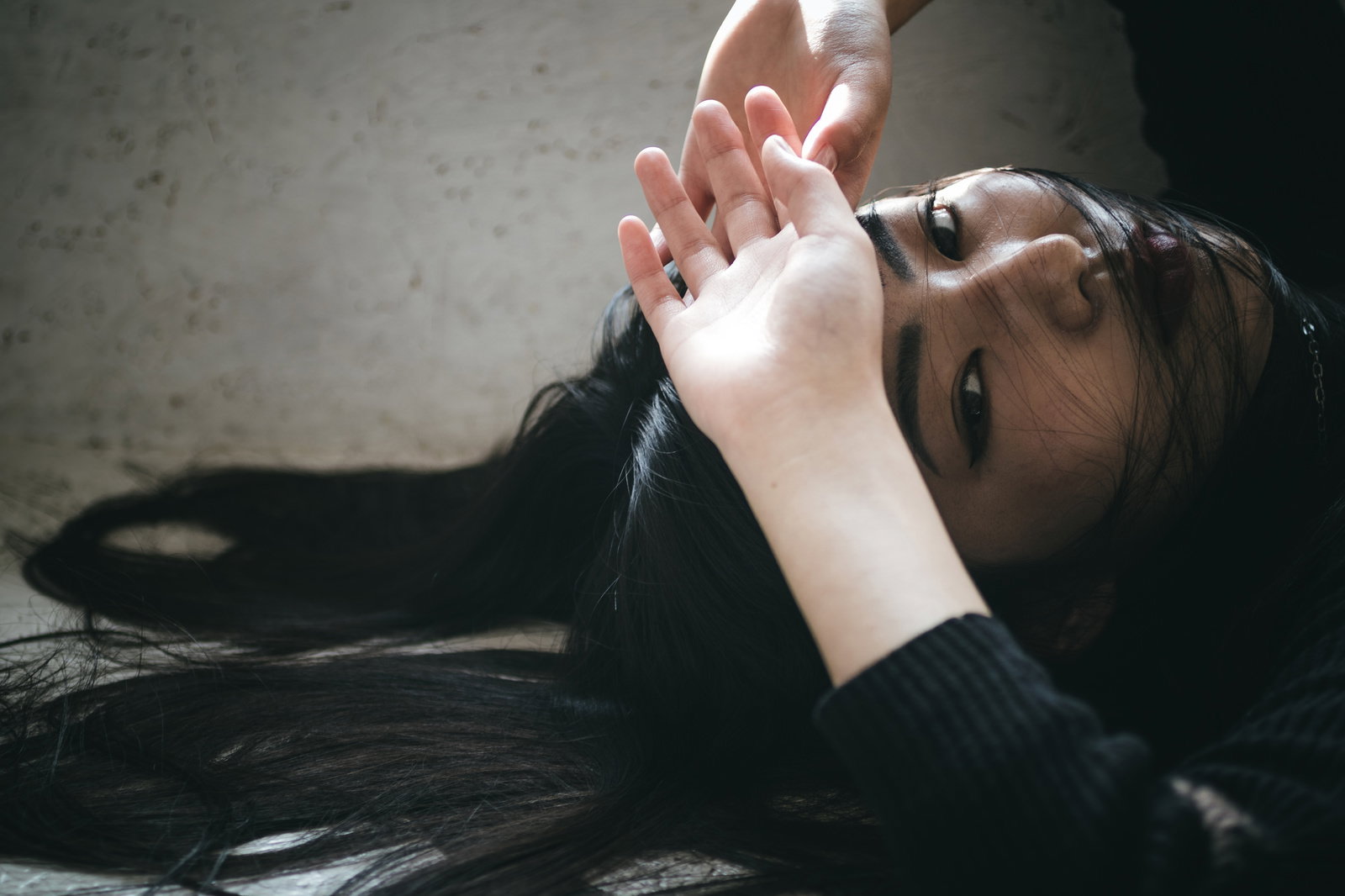 額に手を当てて上向きでポーズをする女性モデル［モデル：なんこ］