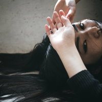 額に手を当てたポージングの女性モデルのファッションポートレートの写真