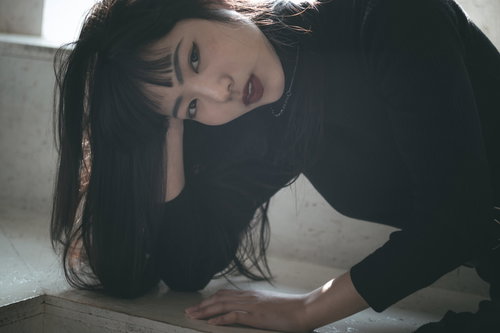 静かな笑みをこぼしながらポージングする黒髪の女性