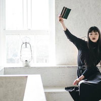 この本、忘れ物です。緑の本を高く掲げる女性のポートレートの写真