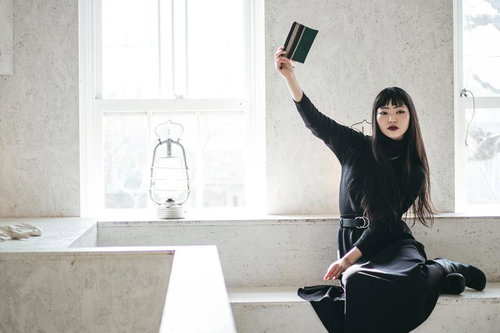 この本、忘れ物です。緑の本を高く掲げる女性のポートレート