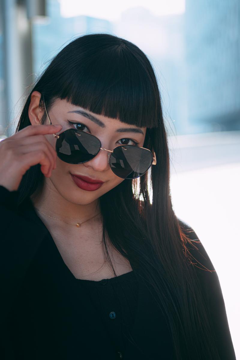 ハート型サングラスをずらす女性のバストアップ［モデル：なんこ］