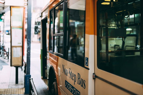 停留所に停車する緑とベージュのノンステップバス