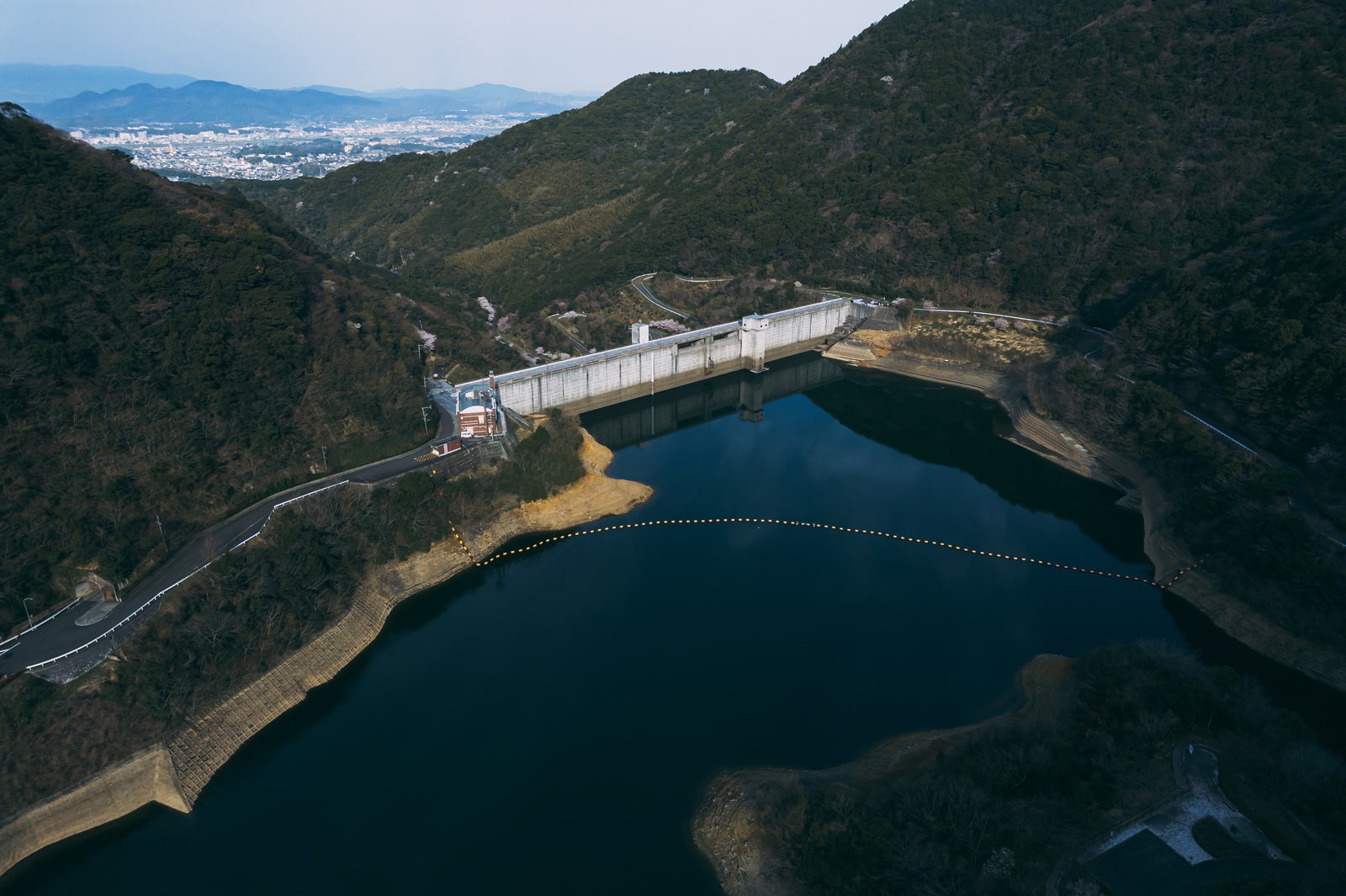 福智山ダムと湖面を空撮で捉えた、山々に囲まれたダム貯水池の風景