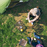 緑の芝生でテントを設営してキャンプする人たちの写真