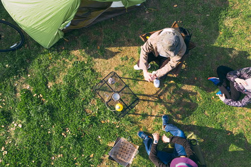 緑の芝生でテントを設営してキャンプする人たち