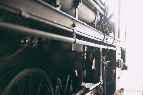 光を浴びる蒸気機関車の足回りと駆動輪、複雑に組み合わさったロッド機構
