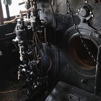 蒸気機関車の機関室に設置された焚口戸とブレーキ弁ハンドルの写真