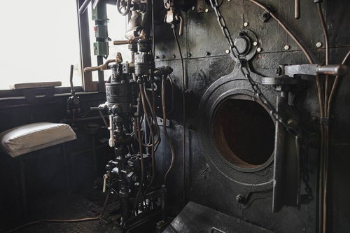 開いたままの焚口戸とブレーキ弁ハンドルが配置された蒸気機関車の機関室