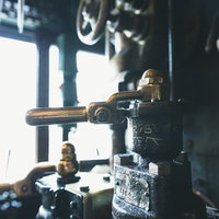 機関室に差す光とブレーキ弁ハンドル、配管とゲージの写真