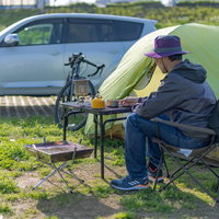 緑の芝生でテント設営するソロキャンプの男性とキャンプ場の写真