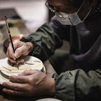 直方市の陶芸職人による焼き物の絵付け作業の写真