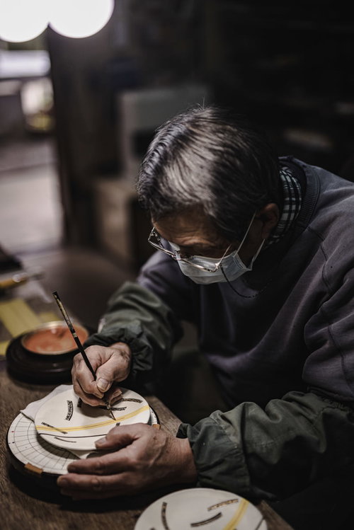 真剣な眼差しで陶器に絵付けをする直方市の陶芸家