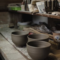 ろくろ台から糸切りされたばかりの陶器と窯元の作業風景の写真