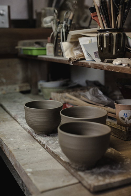 ろくろ台から糸切りされたばかりの陶器と窯元の作業風景