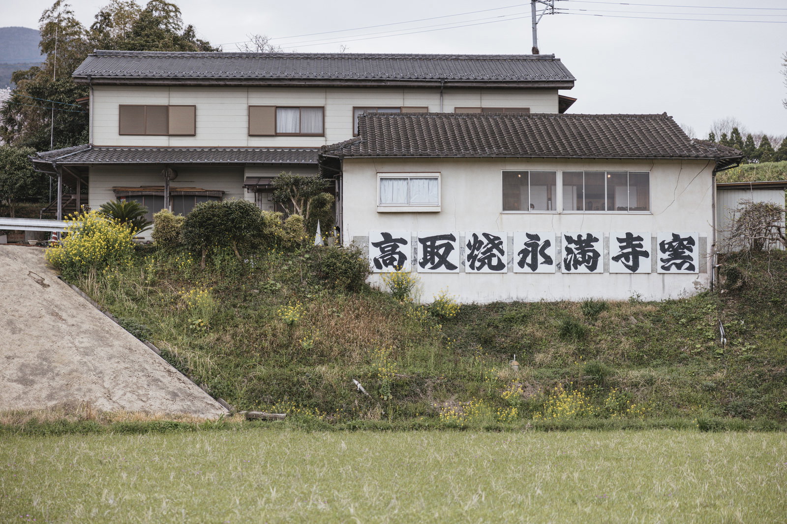 高取焼永満寺窯の看板が設置された白い建物と瓦屋根の日本家屋