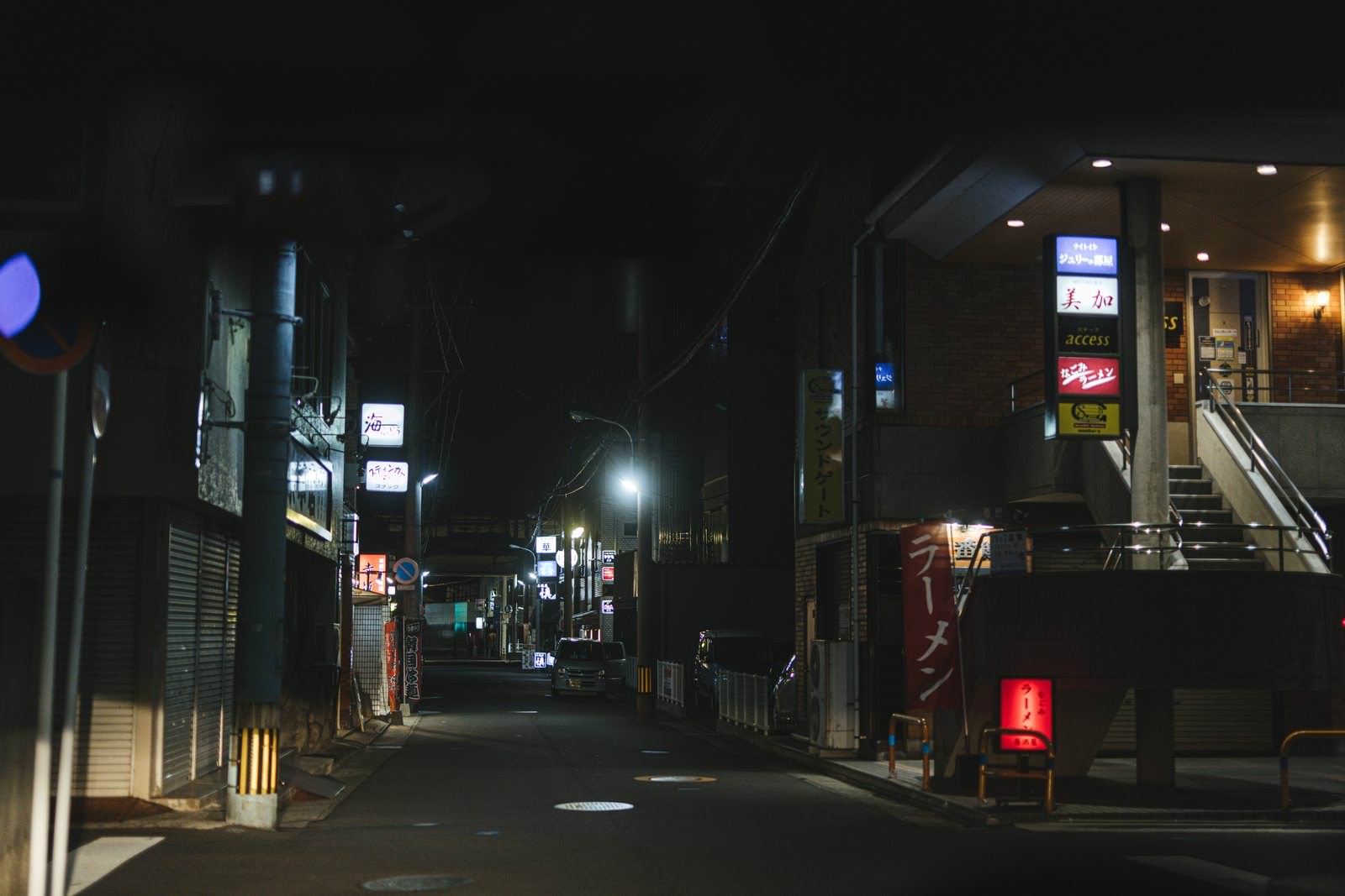 夜の飲み屋街で明かりの灯った店舗と看板が並ぶ路地