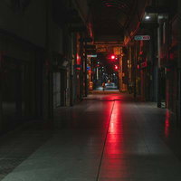 赤信号の光が伸びる深夜の直方市古町商店街の夜景の写真