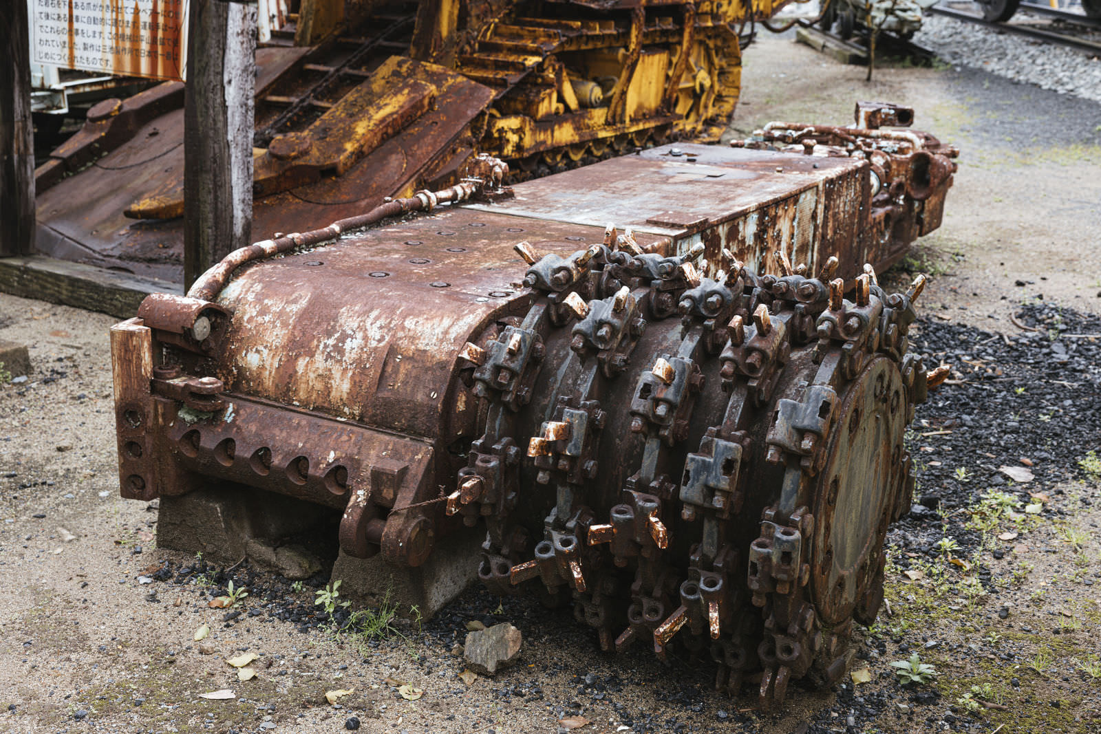 錆びた金属製のドラムカッターが地面に設置されている様子