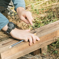 登山道整備用の木の板に彫刻刀で名前を彫る作業の写真